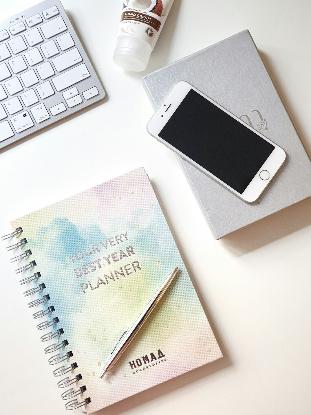 Planner and notebook on a wooden desk with a plant